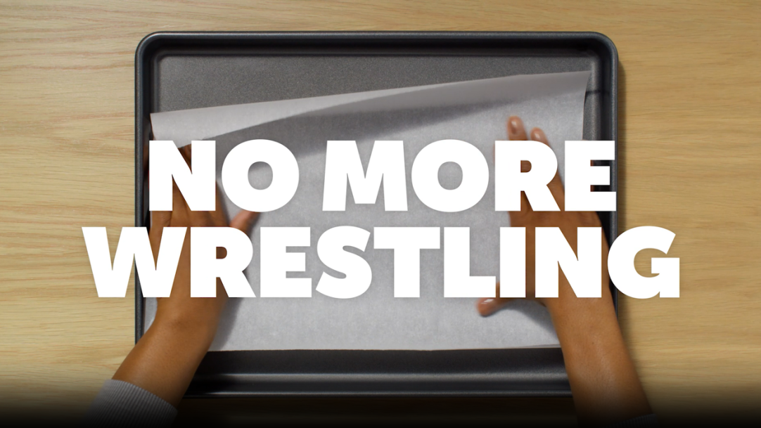 person holding down parchment paper on a baking sheet with curling corners