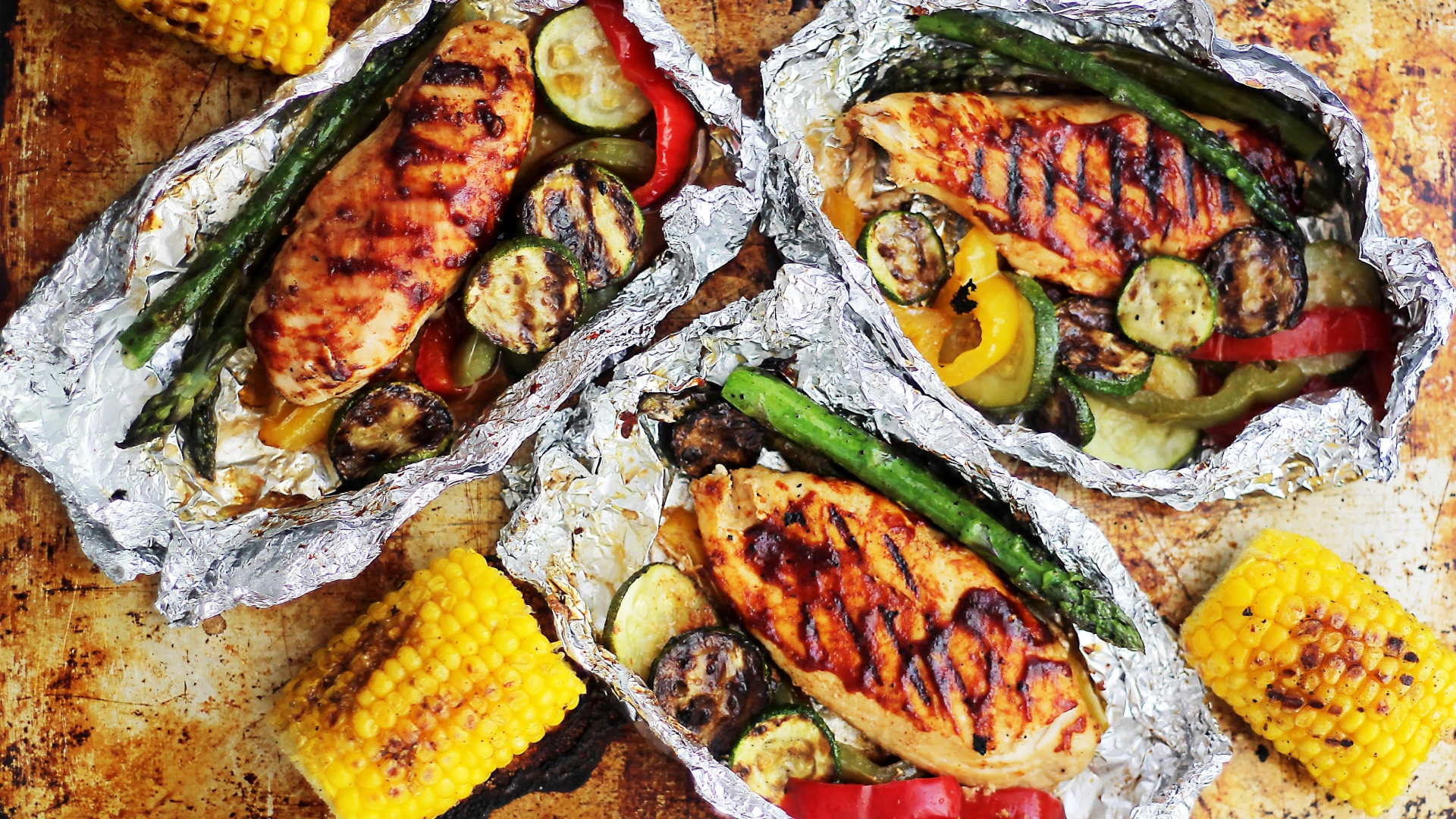 Chicken, asparagus, zucchini and peppers in aluminum foil packets