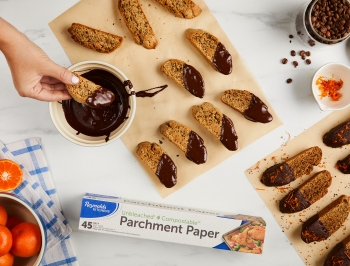 The cooked biscotti are shown being dipped into chocolate and sprinkled with coffee grounds and orange zest