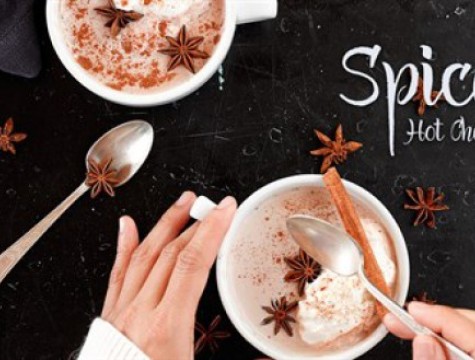Two cups of hot chocolate topped with star anise and cinnamon stick.