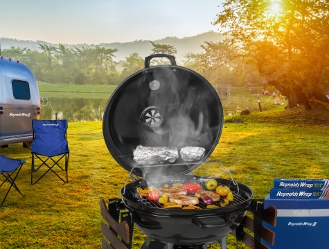 Smoking grill near a trailer with boxes of foil nearby