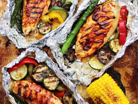 Foil packets with grilled chicken, asparagus and corn inside