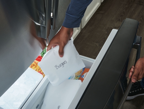 Man placing freezer paper wrapped meat into freezer