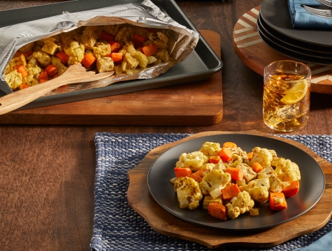 Table setting featuring a plated serving of curried cauliflower and carrots along side an open Reynolds grill bag with additional servings inside