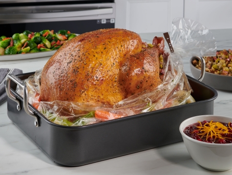 cooked turkey on top of oven bag inside a pan