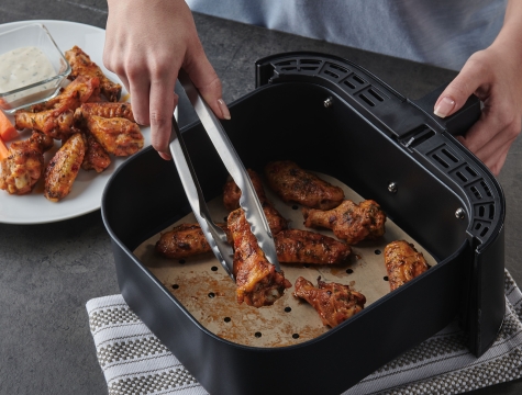 person removing chicken wings from air fryer