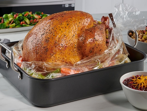cooked turkey on top of oven bag inside a pan