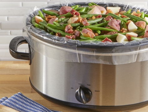 Green beans and potatoes sitting in a slow cooker that is lined with a slow cooker liner