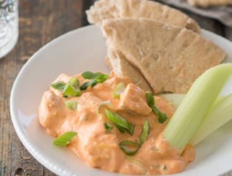 Buffalo chicken dip with celery and pita sitting on a white plate