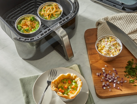 Custom side dishes in air fryer cups sitting alongside an air fryer basket