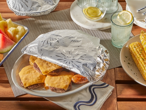 Platter of cheeseburgers partially wrapped in Reynolds Wrap Fun Foil