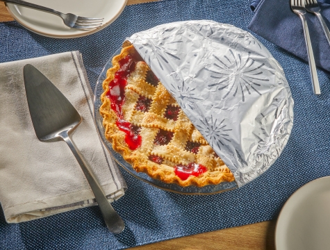 Cherry pie sitting on a table partially wrapped in Reynolds Wrap Fun Foil