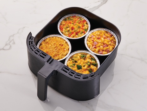 air fryer cups in an air fryer basket filled with different variations of mac and cheese