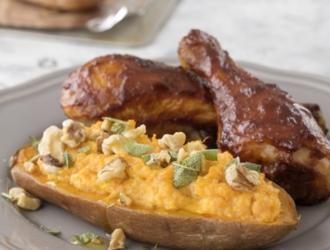 twice baked sweet potato sitting on a plate alongside chicken drumsticks