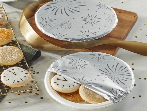 Plate of NYE themed decorated sugar cookies on a plate partially covered with foil