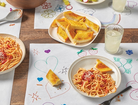 countertop prep paper being used as placemats on a kitchen table topped with bowls of spaghetti
