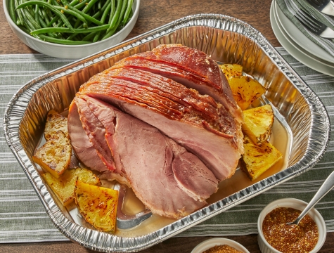 spiral ham in a disposable roasting pan surrounded by diced pineapple 