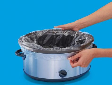 person lining a slow cooker with a Reynolds Kitchens slow cooker liner