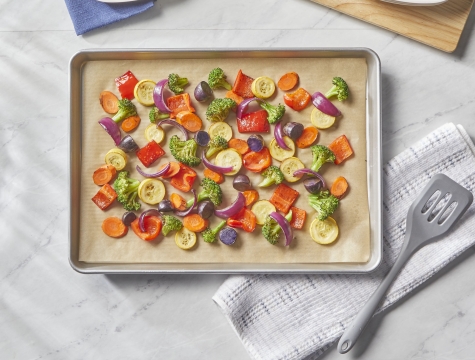 roasted vegetables on a baking sheet topped with unbleached parchment paper