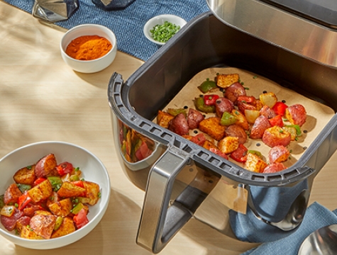 roasted potatoes and vegetables in an air fryer basket lined with a Reynolds Kitchens Air Fryer Liner