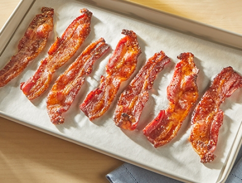 maple glazed bacon sitting on a baking sheet lined with parchment paper