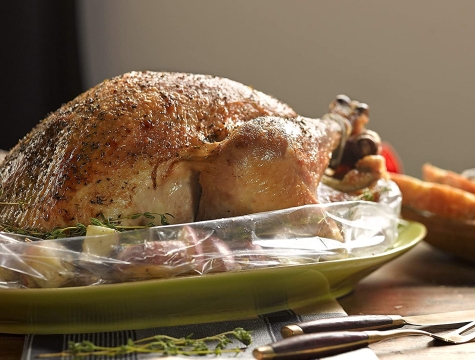 full roasted chicken in an oven bag on a platter sitting on a kitchen table