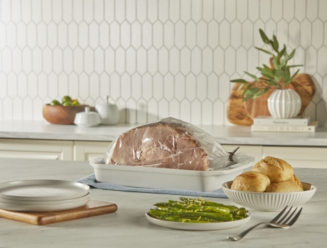 ham in an oven bag sitting on a kitchen island alongside other side dishes