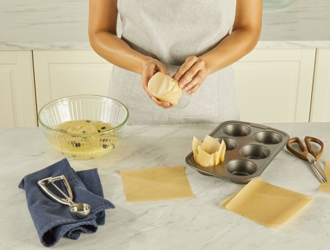 person making a tulip shaped muffin liner out of parchment paper