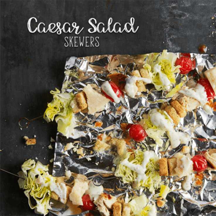 Skewers threaded with lettuce, crouton, cheese, tomato, chicken and topped with dressing set on foil.