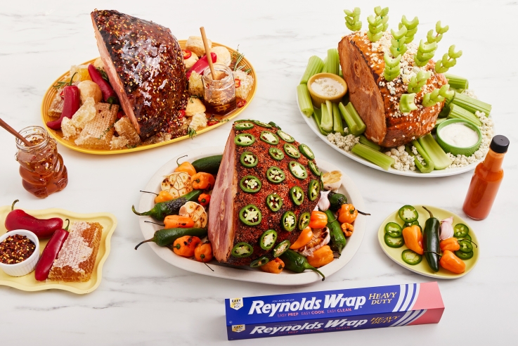 Trio of cooked hams alongside a box of Reynolds Wrap Heavy Duty Foil