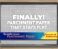 Reynolds Stay Flat Parchment Paper box sitting on top of a parchment lined baking sheet surrounded by cookies