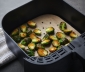 Cooked brussels sprouts lying on an air fryer liner in an air fryer 