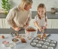 mother and daughter making cupcakes on a kitchen island topped with countertop prep paper