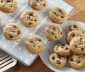 Baked chocolate chip cookies on top of a parchment lined cookie sheet