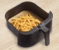 Cooked french fries sitting on top of an air fryer liner in an air fryer basket