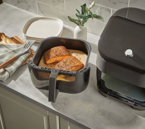 Salmon fillets in an air fryer basket lined with a Reynolds Kitchens Air Fryer Liner