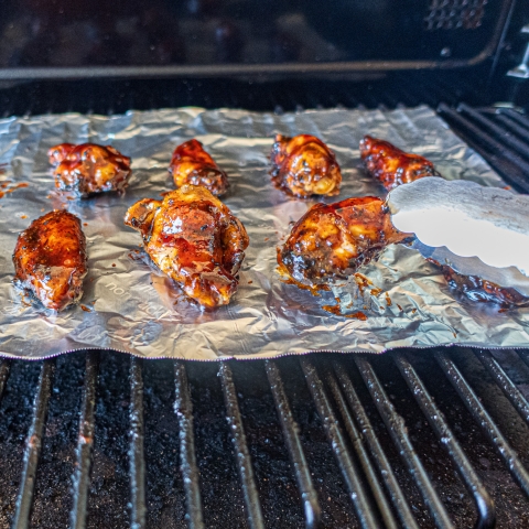 Chicken wings sitting on Reynolds Wrap non-stick aluminum foil on the grill