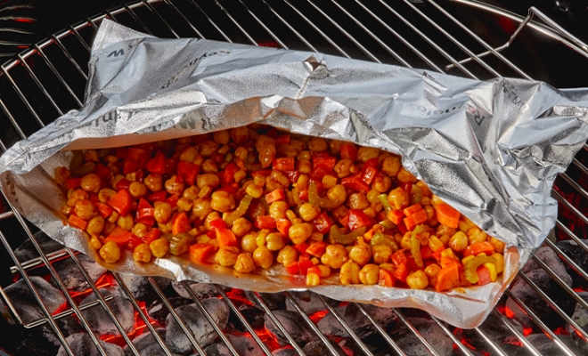 Open aluminum foil grill bag on a charcoal oven with roasted chickpeas inside