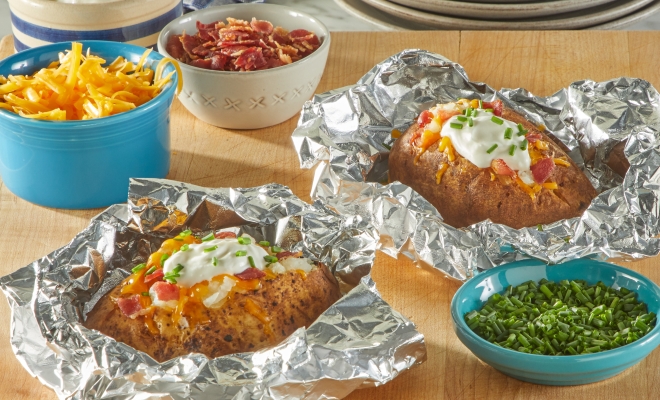 Loaded baked potato sitting in a foil sheet