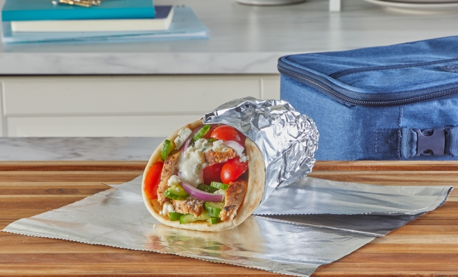 Chicken gyro wrapped in aluminum foil and sitting on a kitchen counter