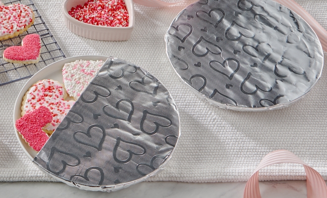 Heart shaped cookies on a plate partially covered in Reynolds Wrap Fun Foil with embossed heart pattern