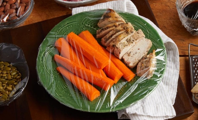 A plate with chicken and carrots wrapped in plastic paper