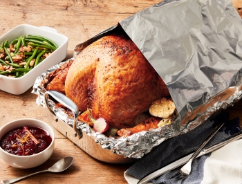 Turkey cooked using the foil tent method with green beans and cranberry sauce nearby