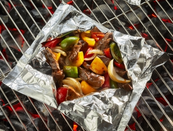 beef and vegetables in a foil packet on a charcoal grill