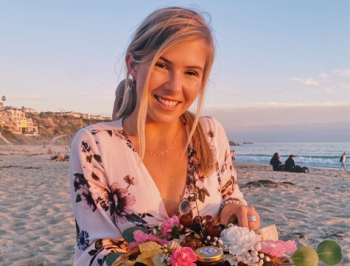 Woman standing on the beach holding a charcuterie board