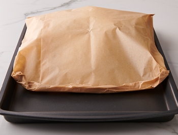 sealed parchment cooking bag sitting on a baking sheet