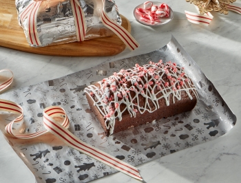 peppermint mocha loaf sitting on a sheet of foil with a wrapped loaf of bread behind tied with a bow