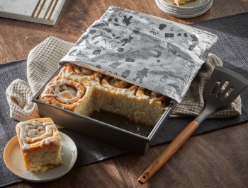 Pan of cinnamon rolls sitting on a table partially covered with foil