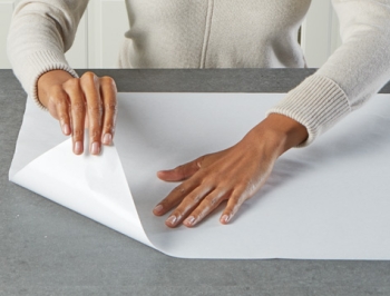 person pressing down countertop prep paper on a kitchen island