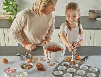 mom and daughter making cupcakes on a kitchen island that has been covered in Reynolds Kitchens Countertop Prep Paper for easy cleanup